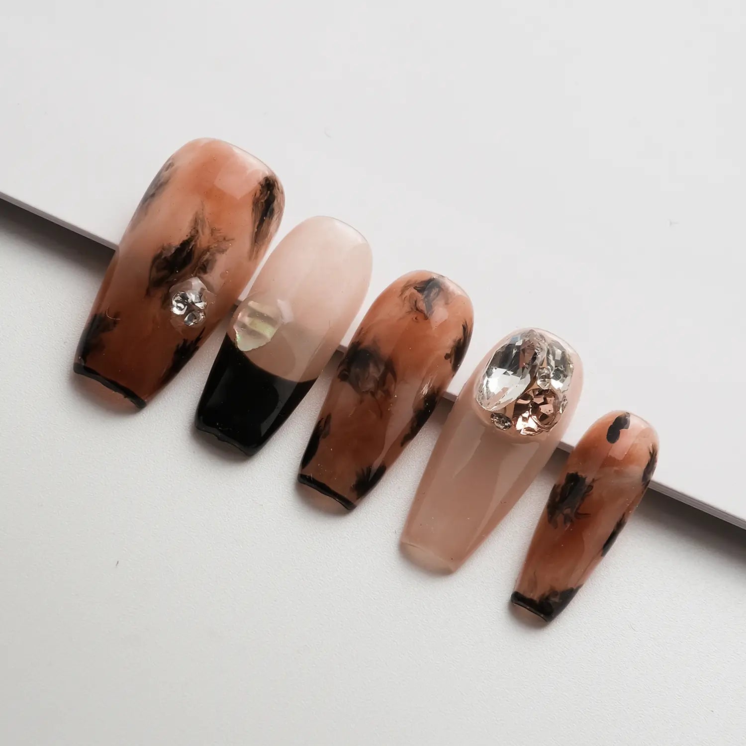 Close-up shots of 5 press-on nails, showing the clear nail shapes and intricate designs.