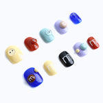 Playful designs feature cartoon-style eyes and press-on nails in bold lettering and bright colors.